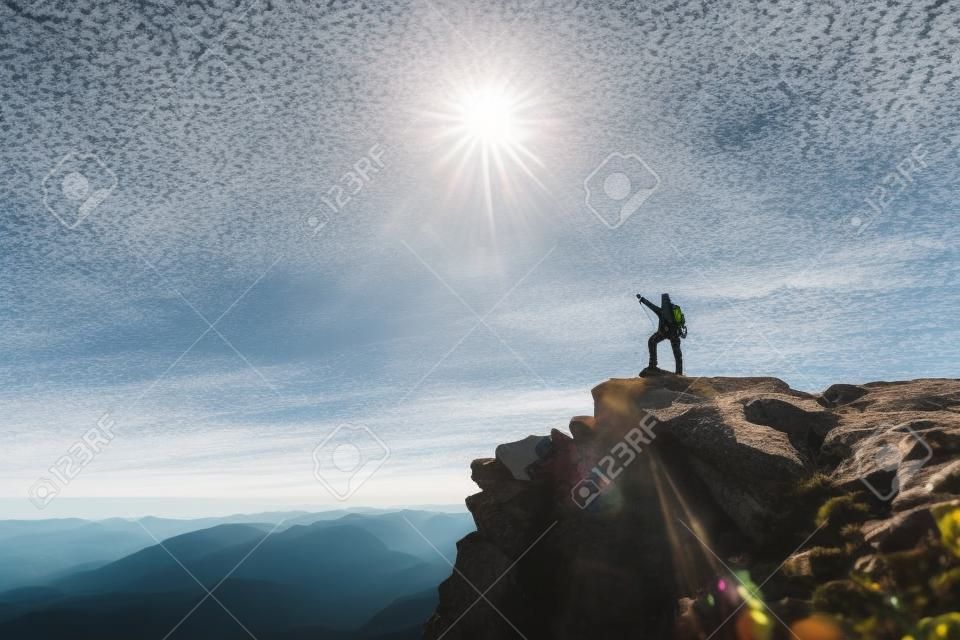 Climber z plecakiem na szczycie w słoneczny dzień, na górze poszedł górzysty mężczyzna, którzy podróżowali po pięknej pustyni.