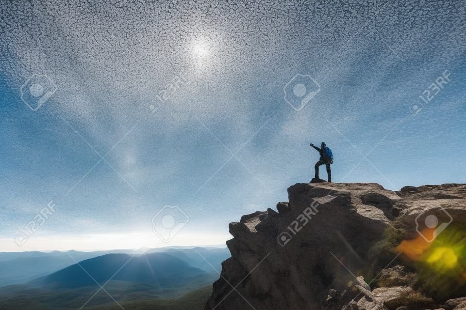 Alpinista com uma mochila no topo em um dia ensolarado, um homem com varas trekking subiu na montanha, as pessoas que viajam através do belo deserto.