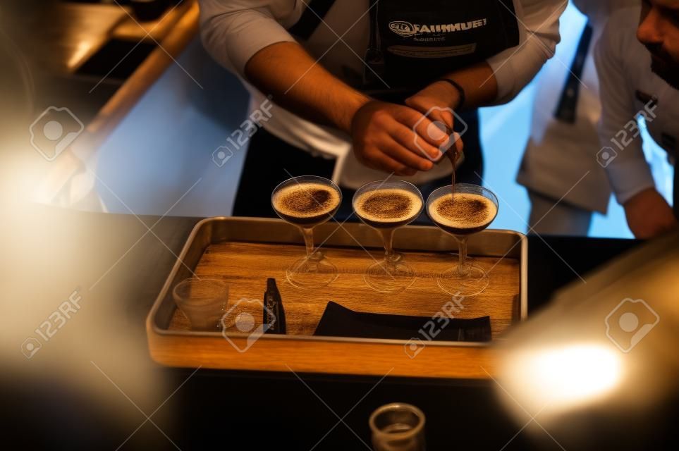 championship among coffee houses, members of teams show barista's skill, prepare drinks, teamwork. pours drink into glasses