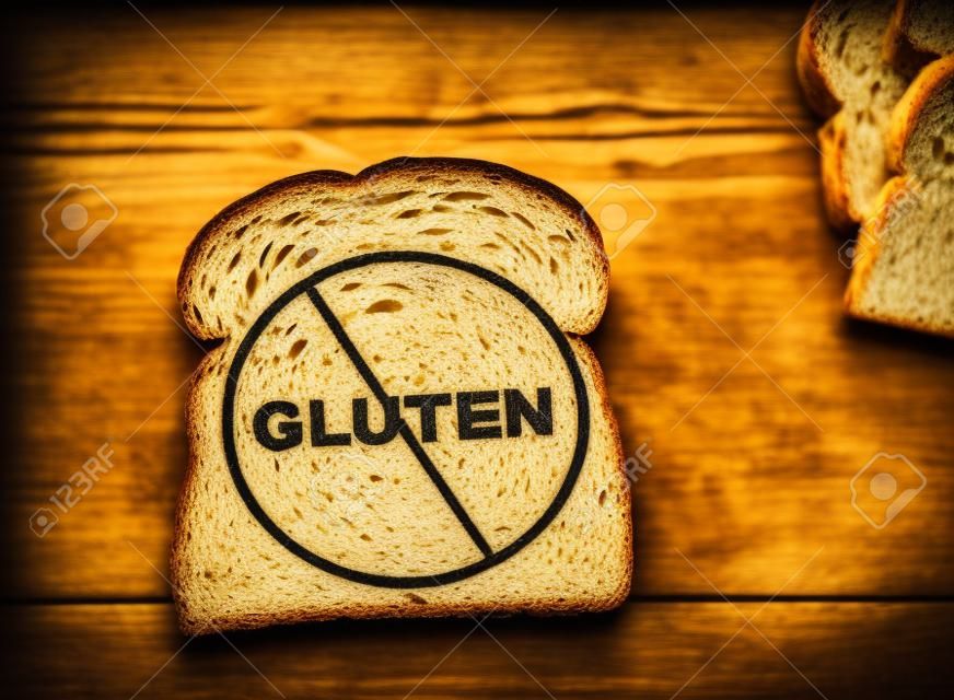 Slice of wheat bread with Gluten text crossed out -- Gluten free concept