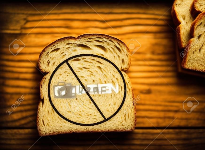Slice of wheat bread with Gluten text crossed out -- Gluten free concept