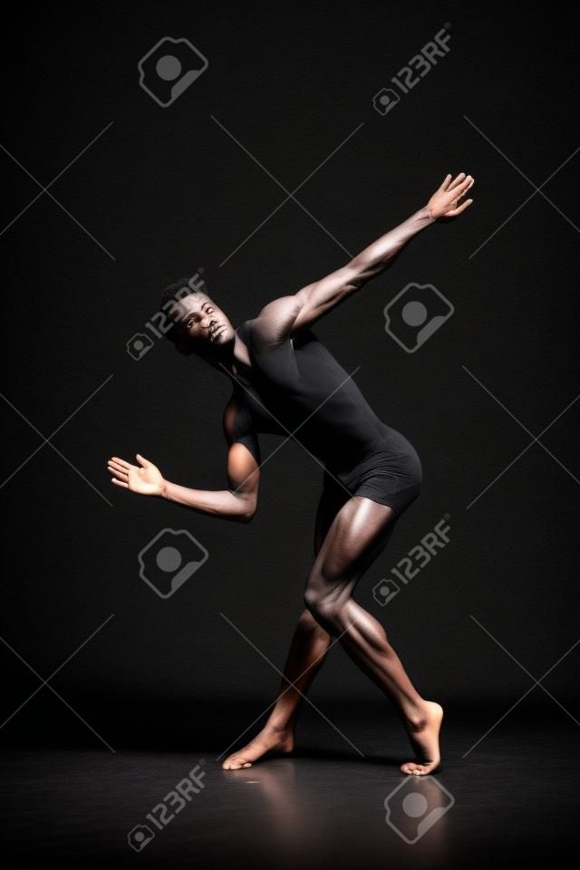 Talented dancer showing his flexibility in the black colored studio