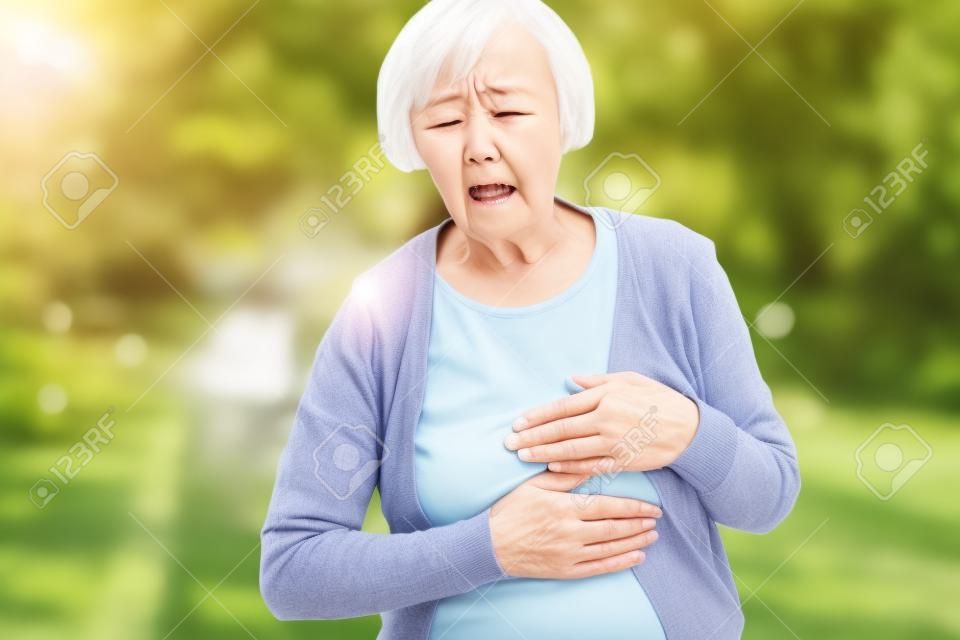 Puzzled aging woman having heart attack outdoors
