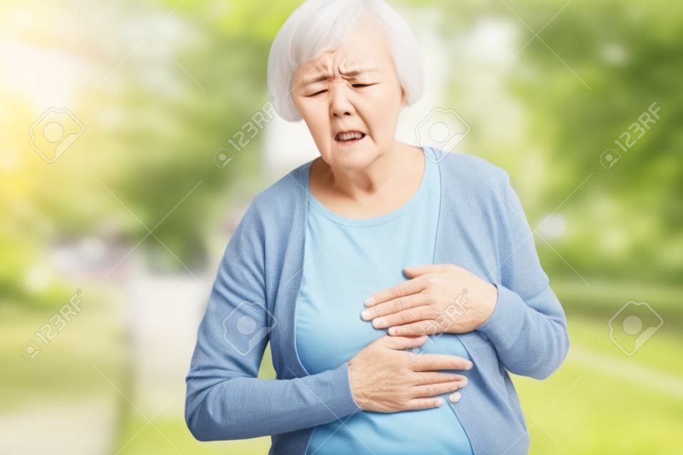 Puzzled aging woman having heart attack outdoors
