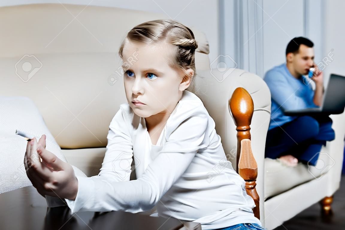 Cigarro. Pobre menina de olhos azuis segurando um cigarro e fumando enquanto seus pais trabalhando em seus laptops