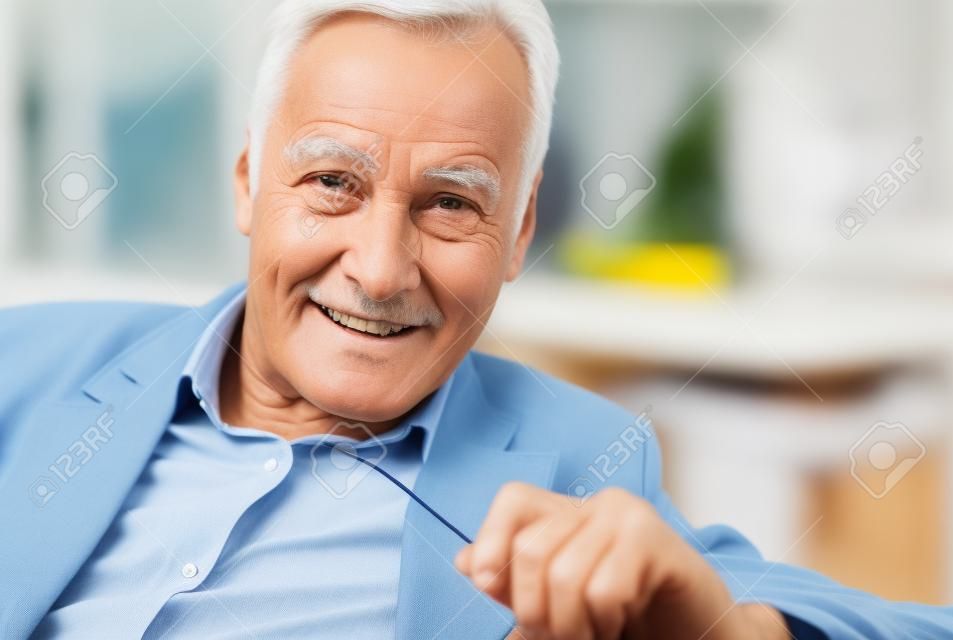 Have a look. Relaxed retired man expressing positivity while looking straight at camera
