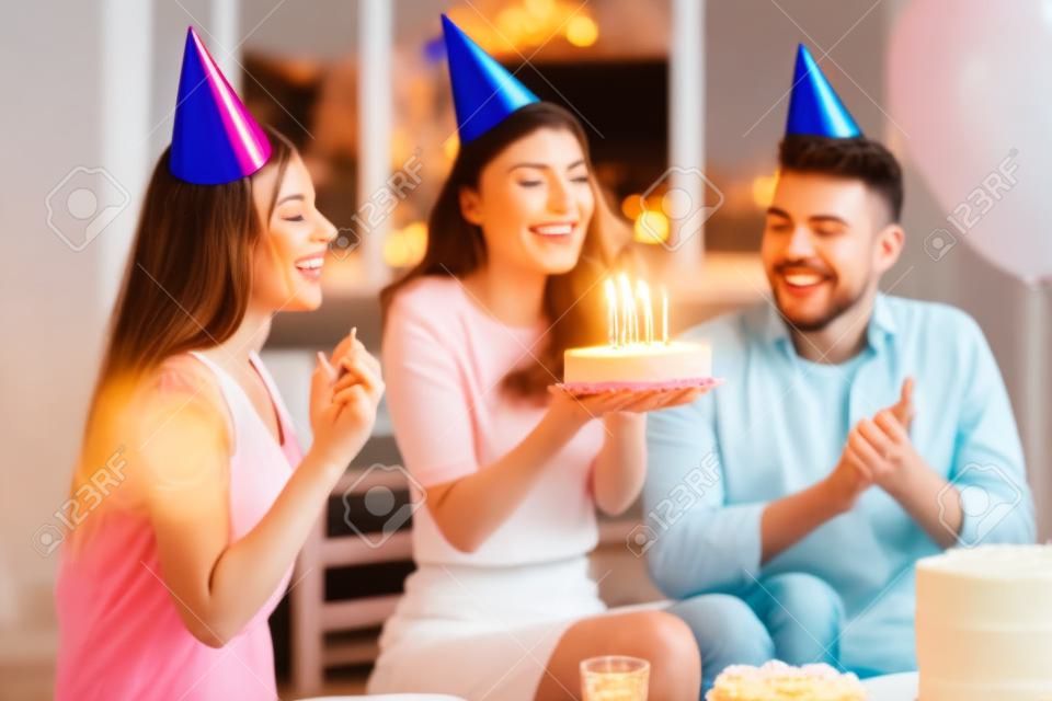 Festa de aniversário. Uma mulher feliz soprando velas em seu bolo de aniversário