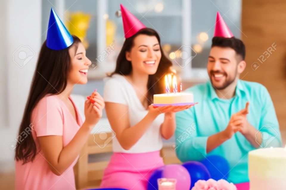 Festa de aniversário. Uma mulher feliz soprando velas em seu bolo de aniversário