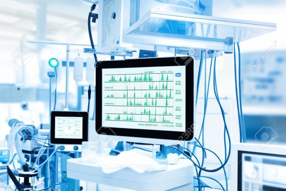 Functional vital functions (vital signs) monitor in an operating room with machines in the background, during real surgery on a patient. Life sustainment, monitoring and anesthesia concept.