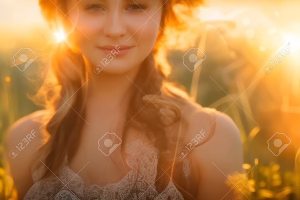 close up portrait of young and tender woman on a feild at sunset