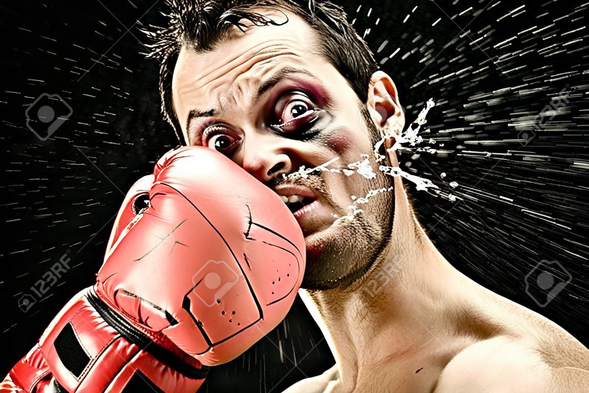 domme bokser man neemt een klap in het gezicht geïsoleerd op zwart. grappig concept portret