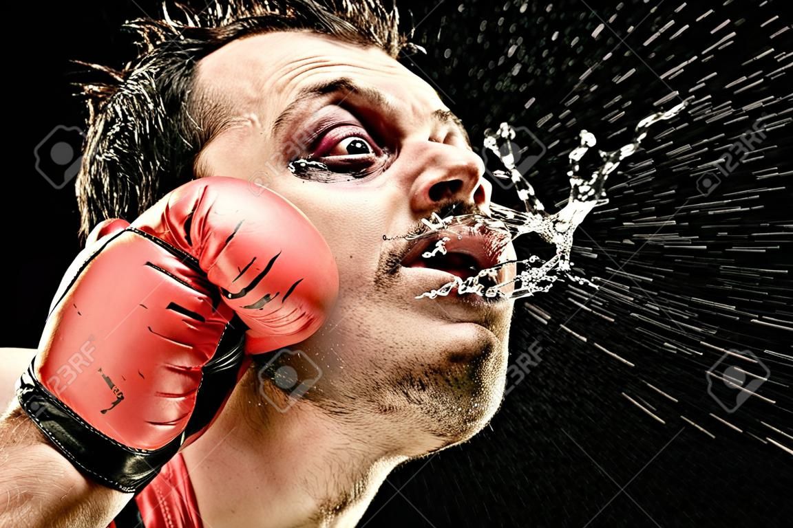 dummer Boxermann nimmt einen Schlag ins Gesicht, das auf Schwarzem lokalisiert ist lustiges Konzeptporträt