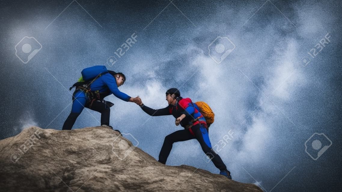 tourists give hand to each other, climbing to top of the hill. team of male travelers goes to victory and success. teamwork of business people. three climbers climb one after another on white rock.