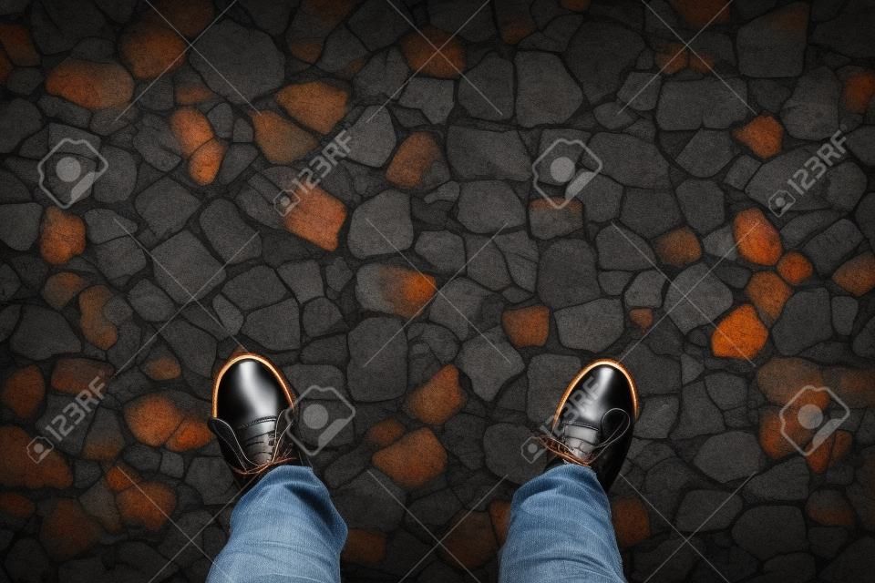 Gumshoes on urban grunge background of cracked asphalt. Conceptual image of legs in boots on city. Feet shoes walking in outdoor. Youth Selphie Modern hipster.