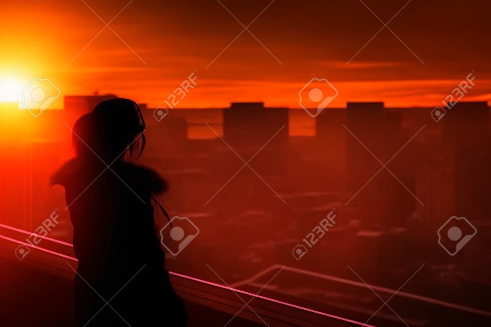 Sziluettje nő élvezi a városra néző naplemente. Concept a magány, az örökkévalóságot, a választás