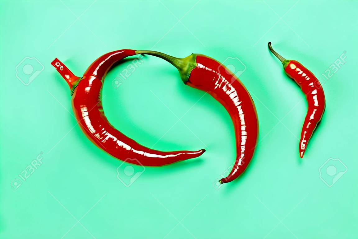 Two Hot Red Chili Peppers Form Yin Yan a Symbol on Green Background. Flat Lay.