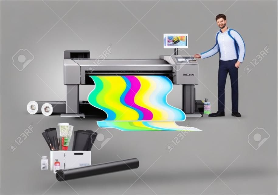 Man printing at plotter wide format banner with coloful ink. Printshop and polygraphy office