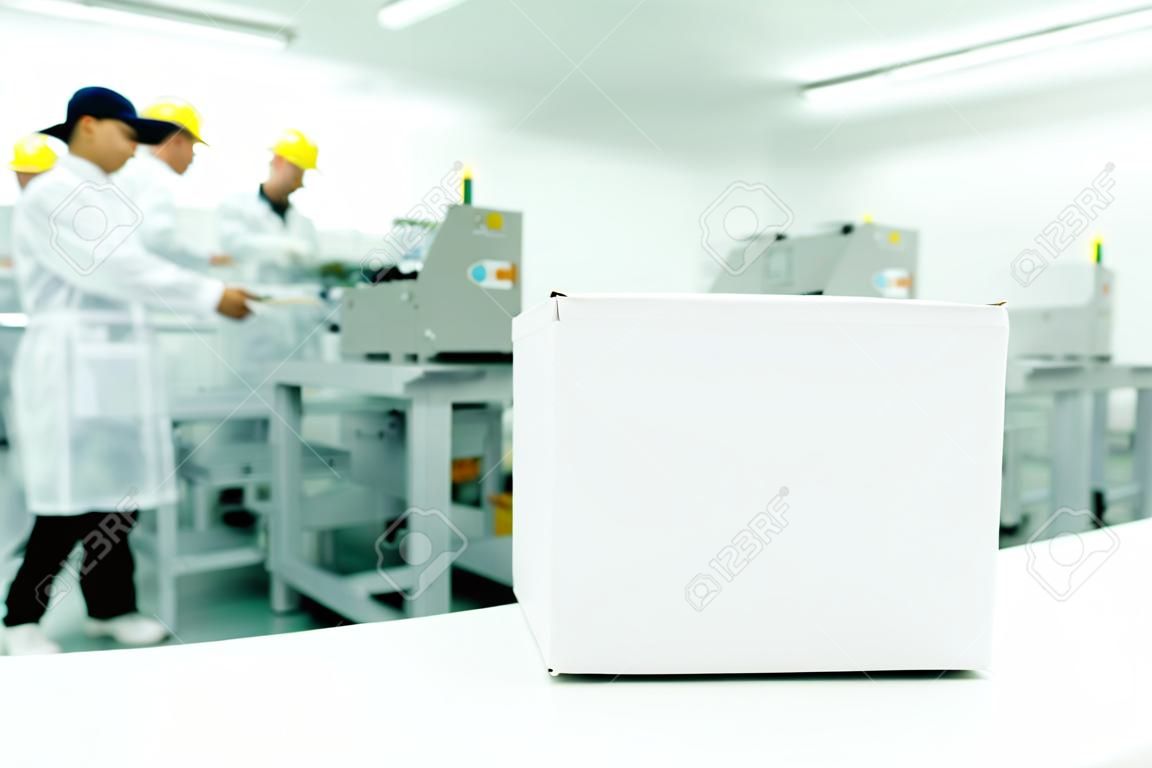 White box at automated production line at modern factory, people working in background