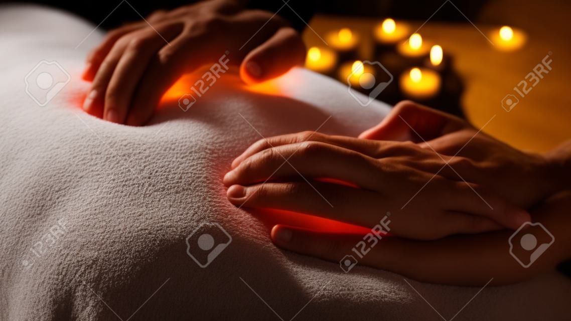Nahaufnahme - Masseurhände bei Rückenmassage im Spa-Center, Studio. Warme romantische Beleuchtung, zurückhaltend. Wellness-, Entspannungs- und Gesundheitskonzept
