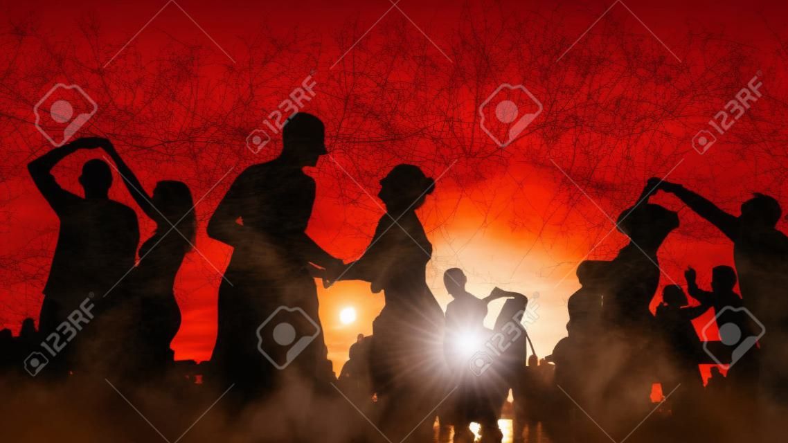 Many unrecognizable people silhouettes dancing on city embankment against sky at sunset. Warm illumination. Romantic pairs group dance, outdoor activity and leisure time concept