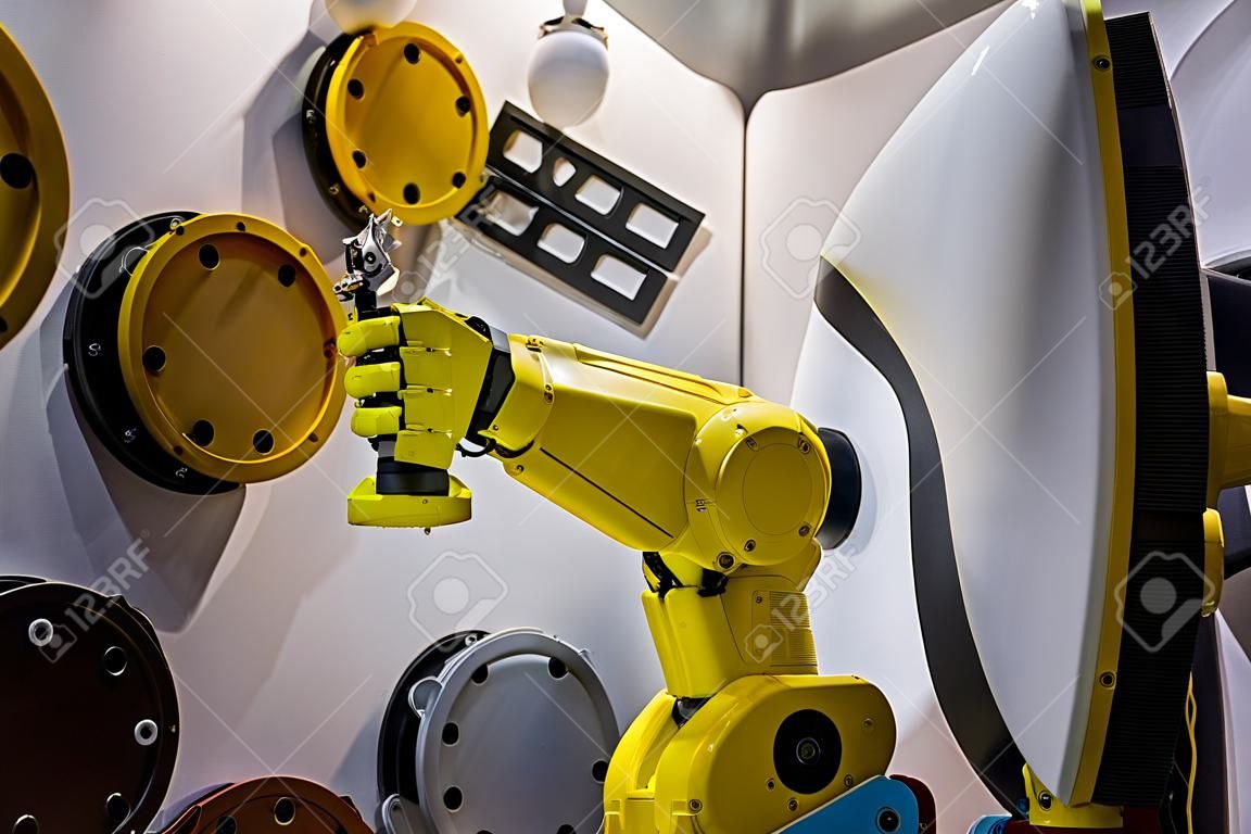 Il manipolatore automatico del braccio robotico con verniciatura a spruzzo gialla dimostra la funzionalità alla mostra sulla tecnologia dei robot intelligenti, alla fiera commerciale. Produzione, futuristico, concetto di produzione