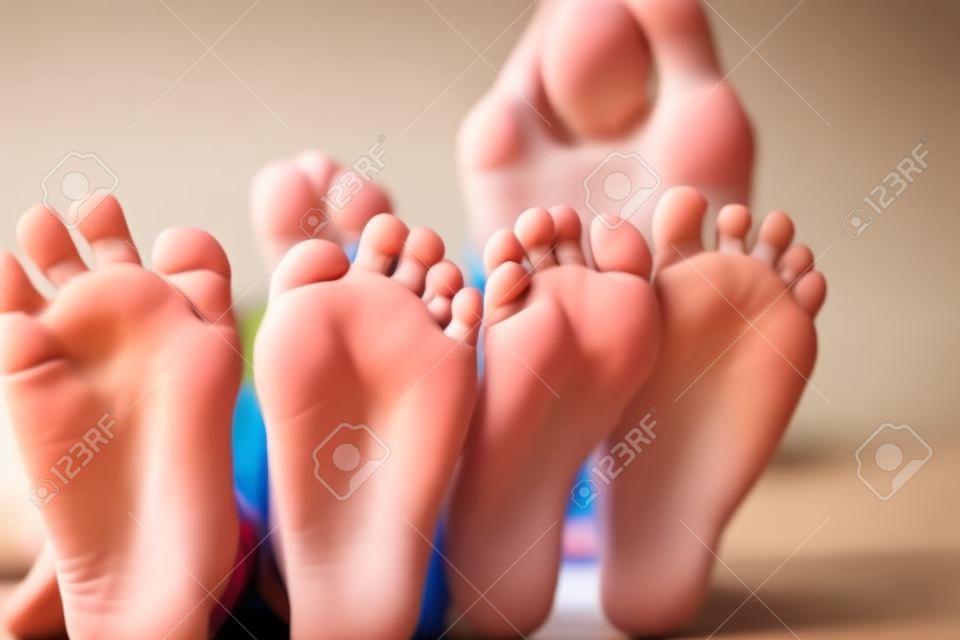 Childrens feet close up to the camera. Their blurred faces in a background.